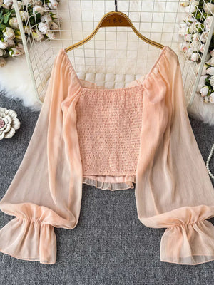 Peach smocked maternity blouse with ruffled bell sleeves and square neckline.