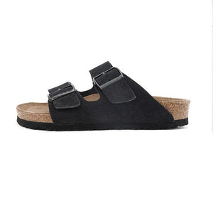 Black suede slide sandals with adjustable buckle straps and cork footbed.