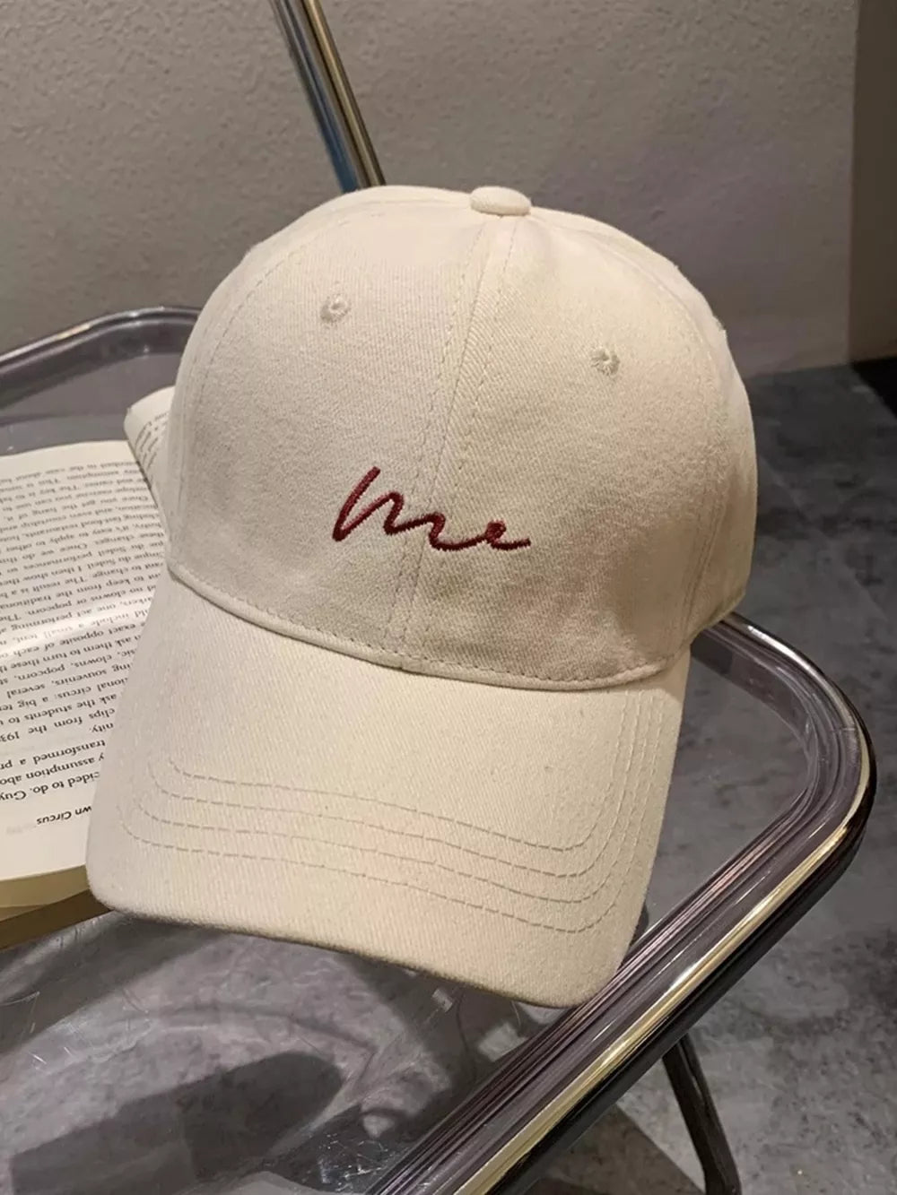 Beige white baseball cap with embroidered red "me" text detail