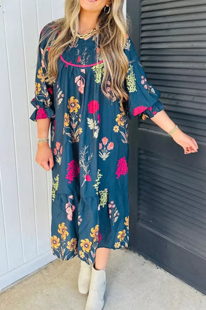 Midi dress in navy with a floral print, smocked bodice, pink trim, and ruffled sleeves.