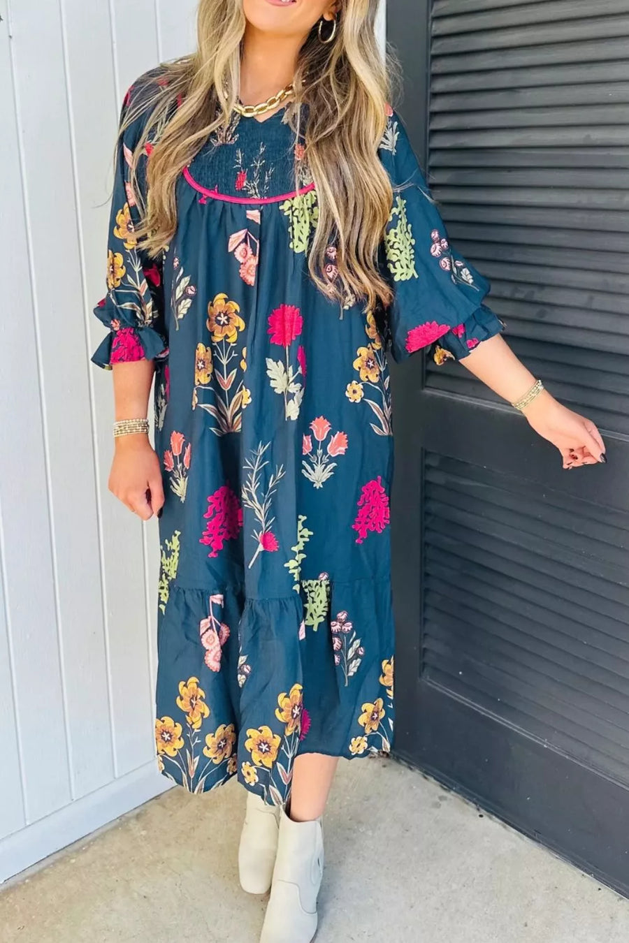 Midi dress in navy with a floral print, smocked bodice, pink trim, and ruffled sleeves.