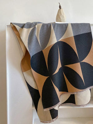 Soft scarf with geometric pattern in black, tan, grey, and cream with fringe details.