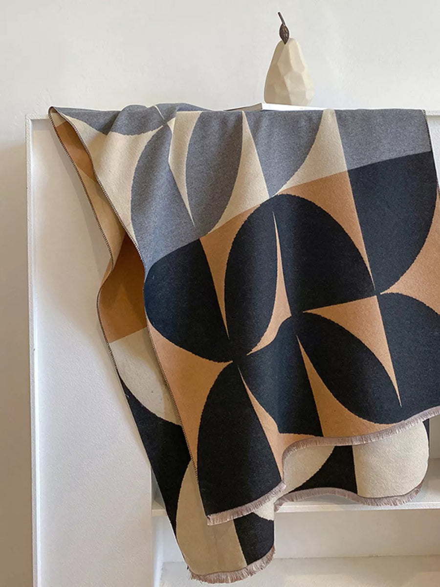 Soft scarf with geometric pattern in black, tan, grey, and cream with fringe details.