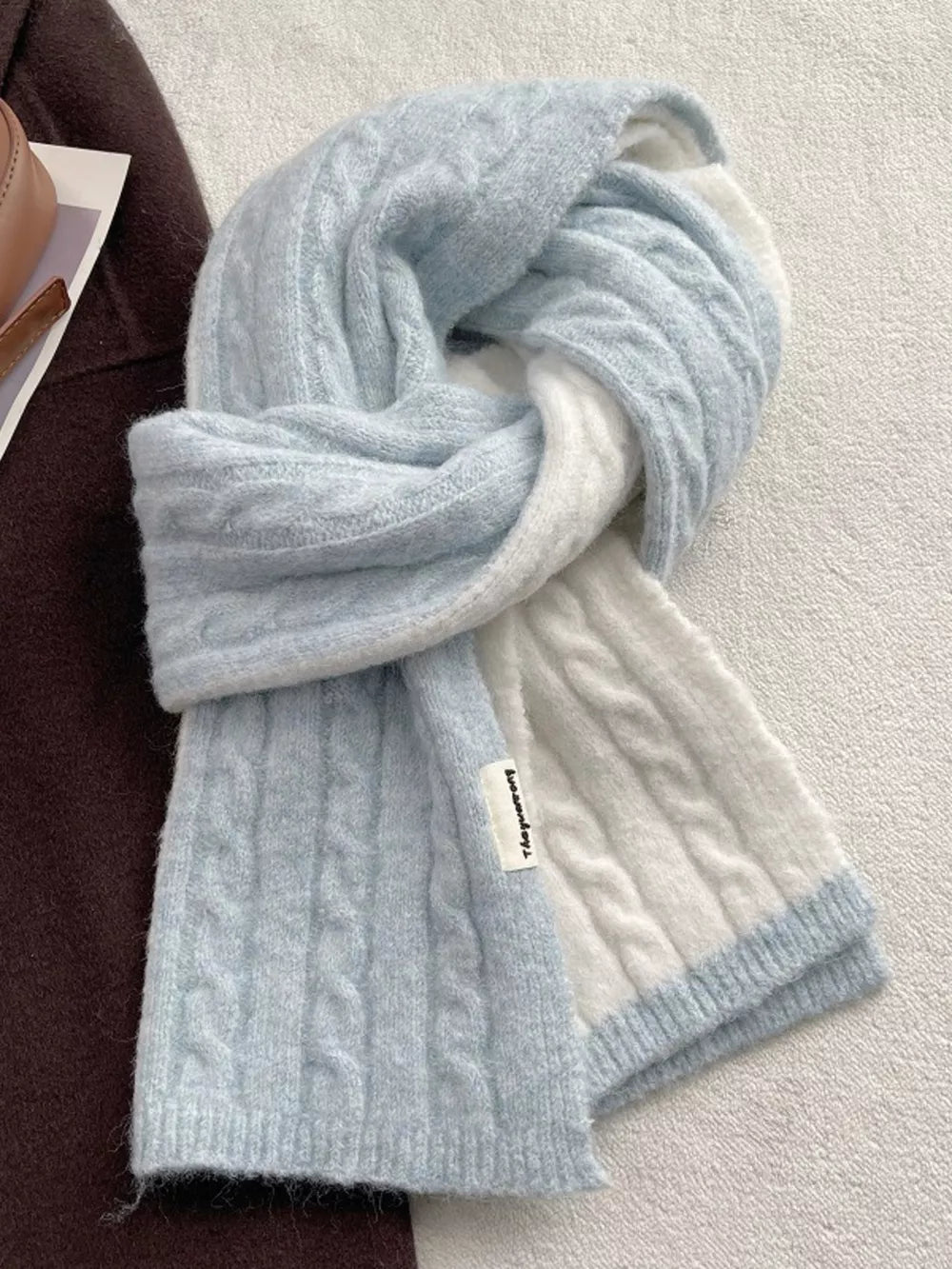 Textured two-tone wool blend scarf in light blue and white with cable knit pattern.