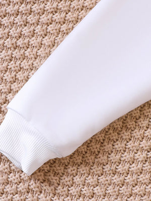 White baby sweatshirt sleeve with ribbed cuff on textured background