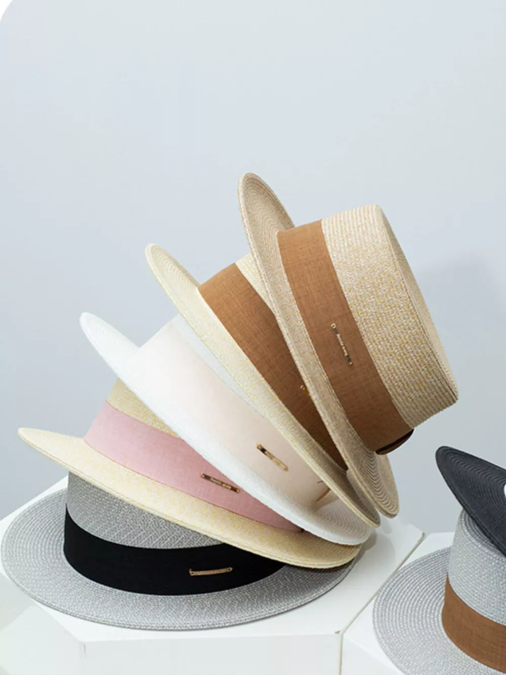 Straw boater hats in beige, blush pink, gray, and black with ribbon details.