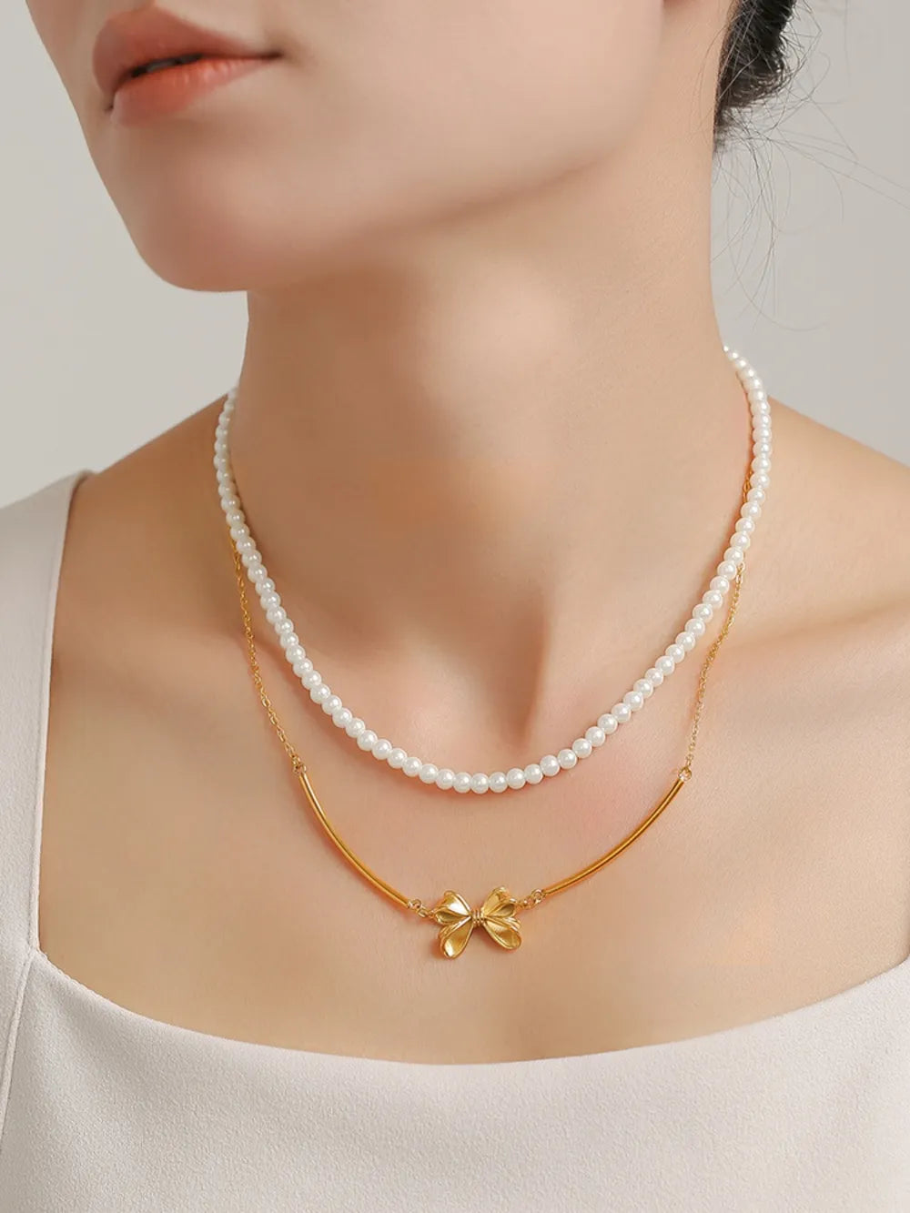Gold layered necklace set with pearls and a bow charm.