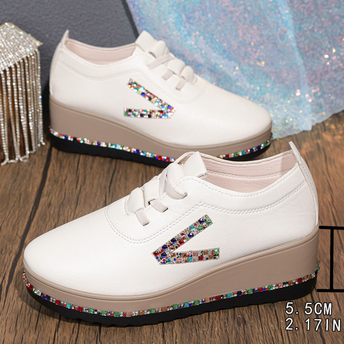 White wedge sneakers with colorful rhinestone embellishments on the side and sole.