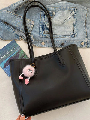 Black PU leather tote bag with a fluffy pink charm and denim jacket detail.