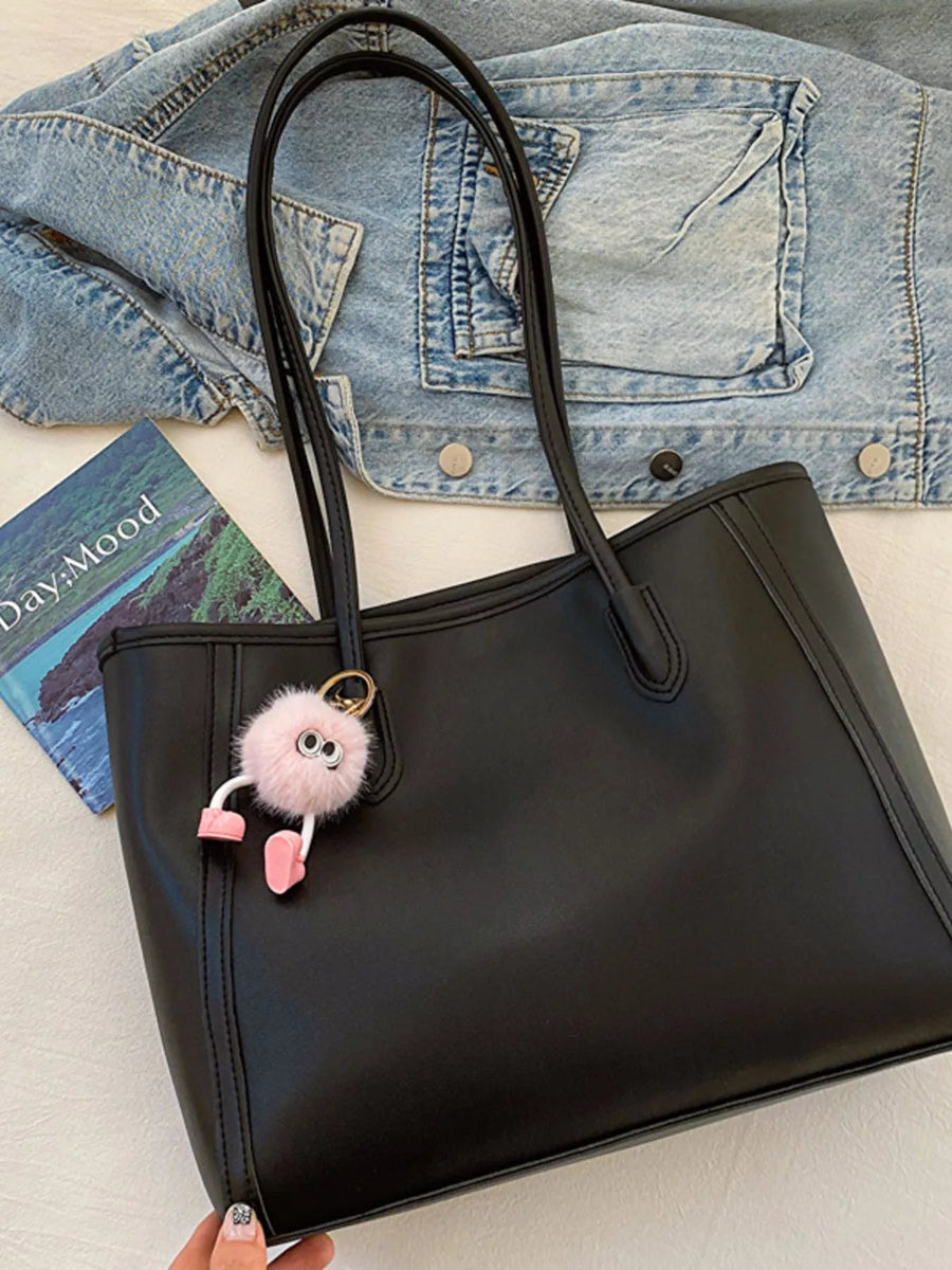 Black PU leather tote bag with a fluffy pink charm and denim jacket detail.