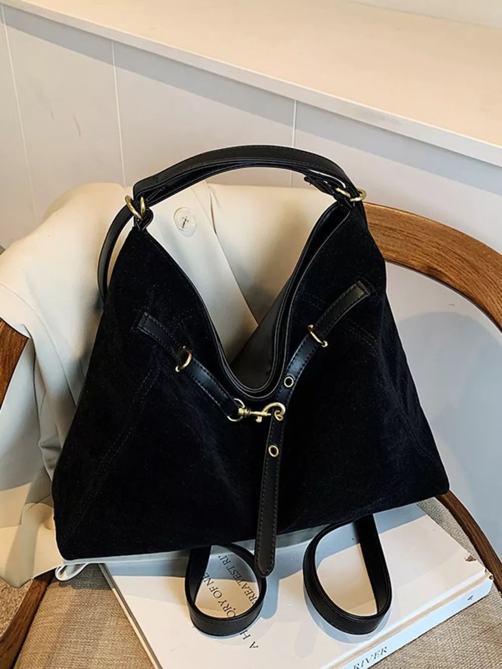 Black slouchy crossbody bag with gold accents and adjustable strap.