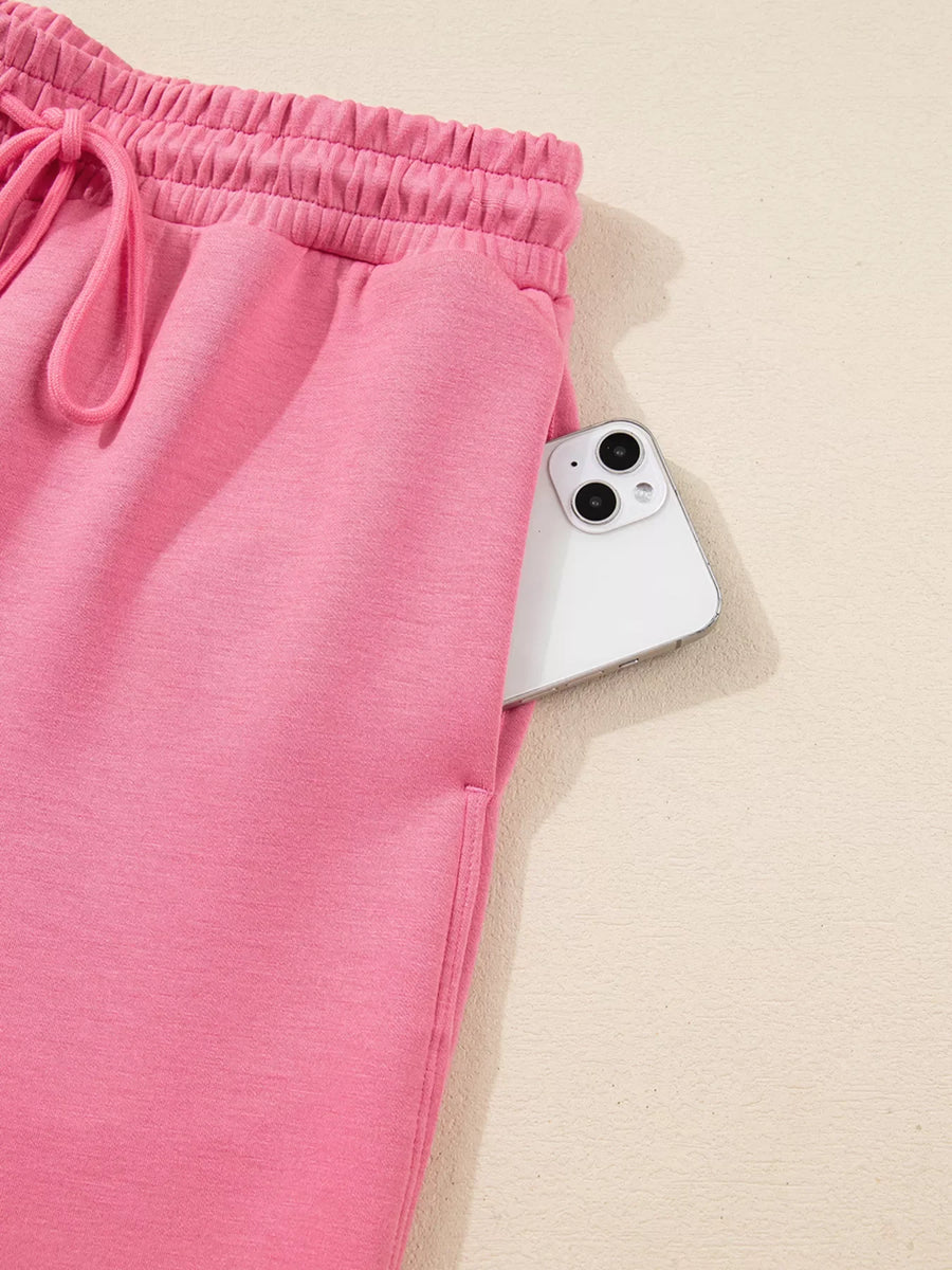 Dusty pink drawstring pants with elastic waist and side pocket holding a phone.