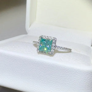 Silver ring with square teal moissanite center stone and diamond halo.