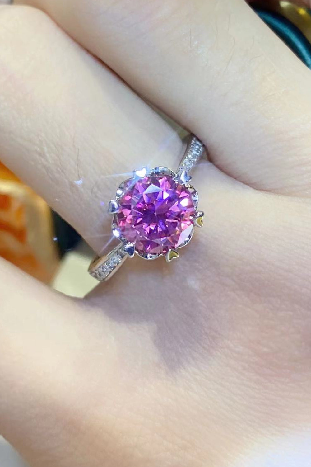 Pink moissanite ring in sterling silver with floral-inspired setting and diamond accents.
