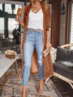 Terracotta velvet duster coat with fluid silhouette, open front, long sleeves, worn with jeans and heels.
