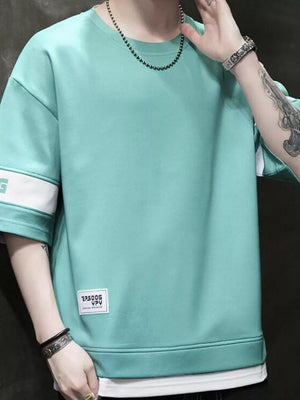 Light green oversized t-shirt with contrast white sleeve bands and a graphic tag.