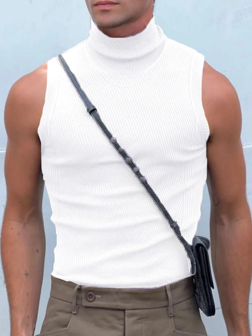 White ribbed sleeveless turtleneck shirt with a high neck, worn with a crossbody bag.
