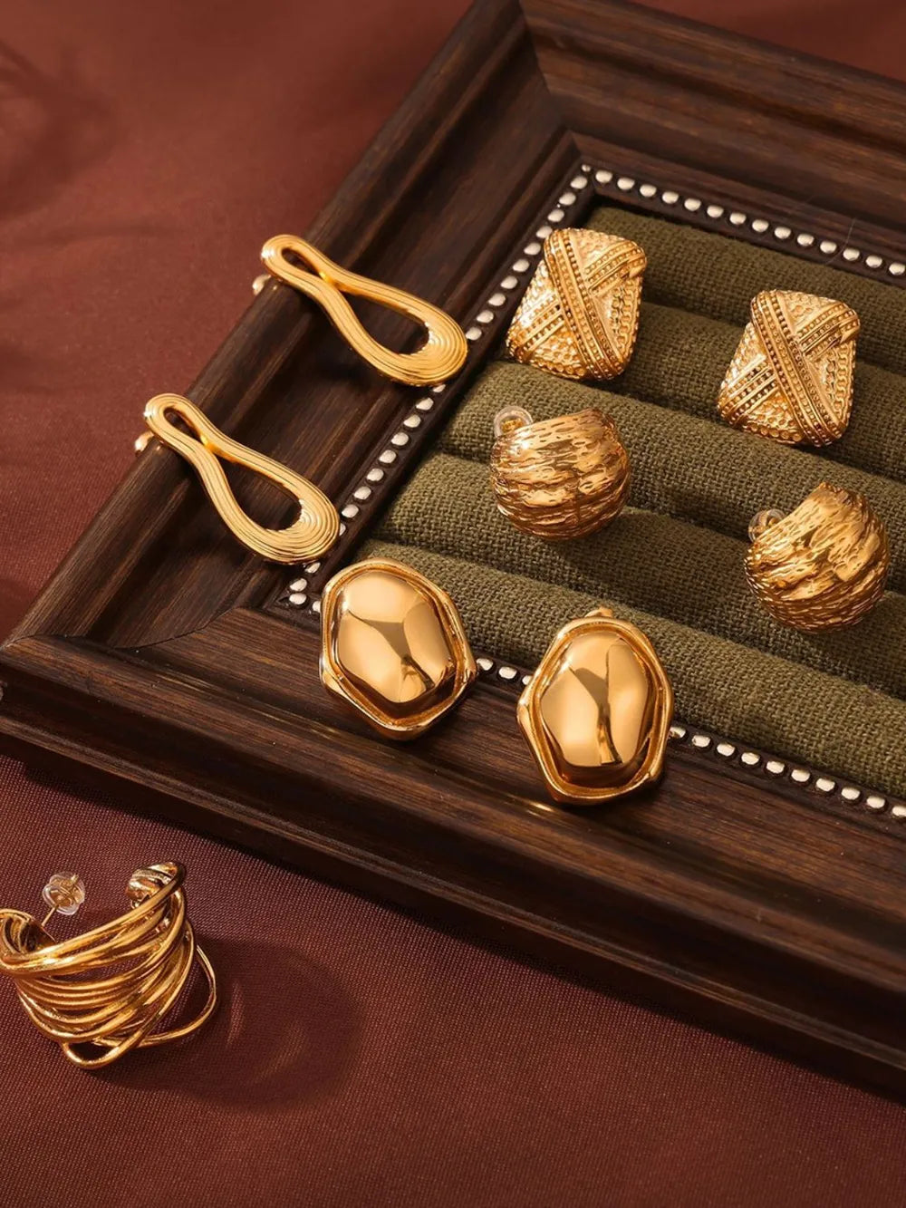 Gold-tone earrings collection featuring sculptural shapes, textured finishes, and a modern hoop style.