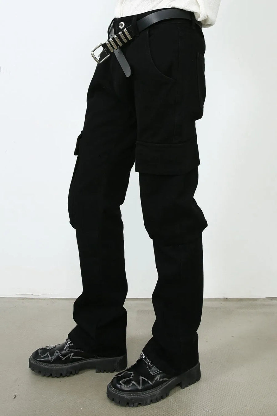 Black denim utility trousers with cargo pockets and a layered cuff detail.