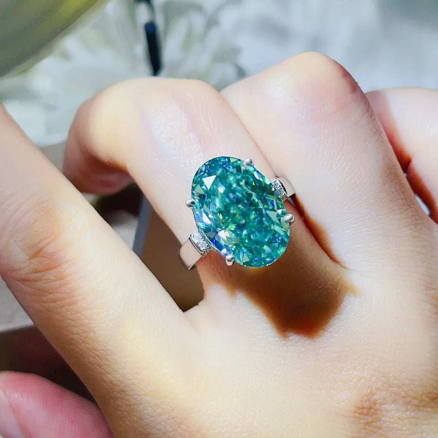Emerald cut turquoise moissanite cocktail ring with small accent stones on a silver band.