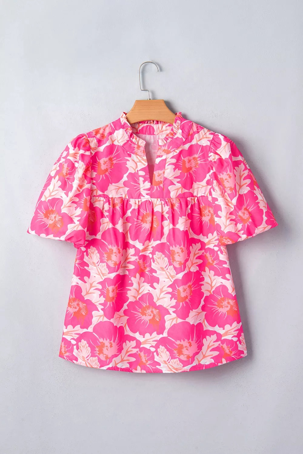 Vibrant floral print polyester blouse with ruffled neckline and bubble sleeves.