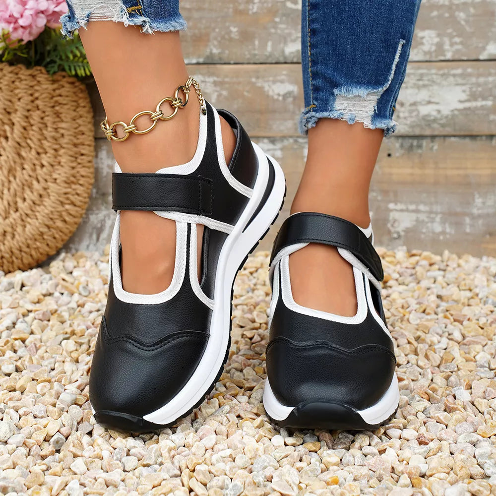 Black Mary Jane cutout sneakers with white contrast trim and adjustable straps.