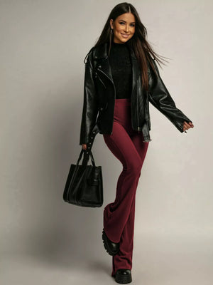 High-waisted flared trousers in red, styled with a black leather jacket and handbag.