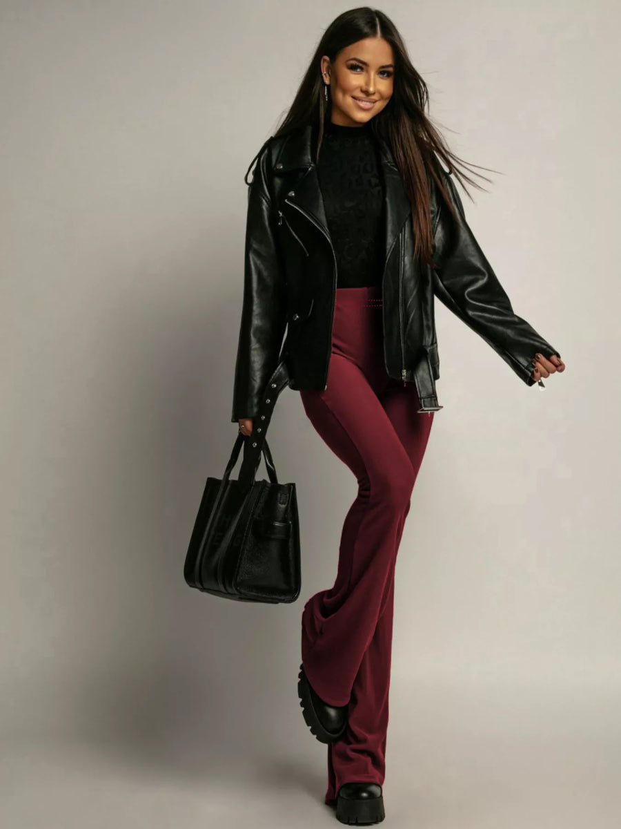 High-waisted flared trousers in red, styled with a black leather jacket and handbag.