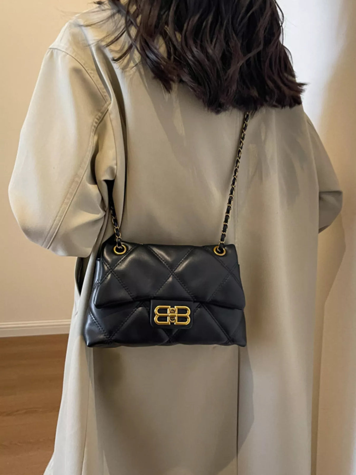 Black quilted flap chain shoulder bag with gold hardware and a unique clasp.