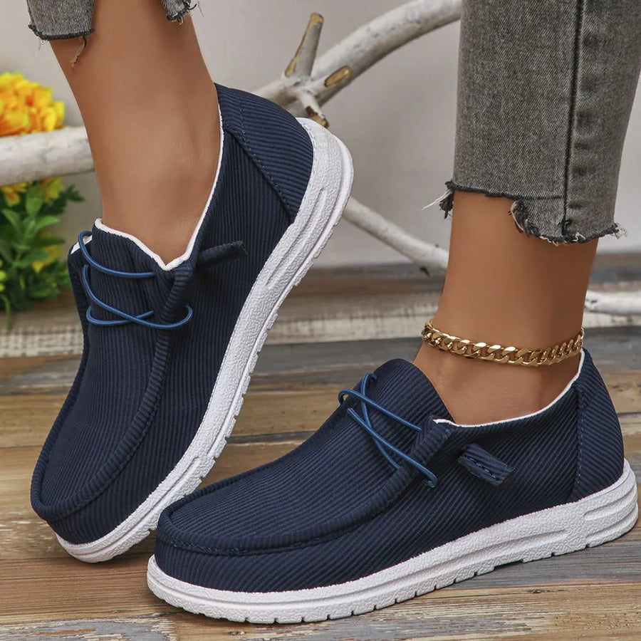 Navy textured slip-on espadrille sneakers with white soles and blue laces.