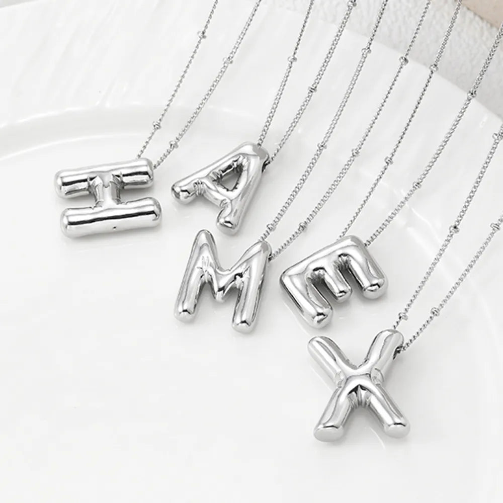Sculpted initial pendant necklaces in silver with beaded chains, featuring bubble letters.