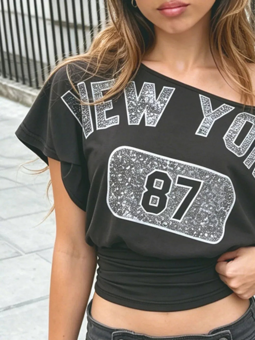 Black one-shoulder top featuring ruched and graphic