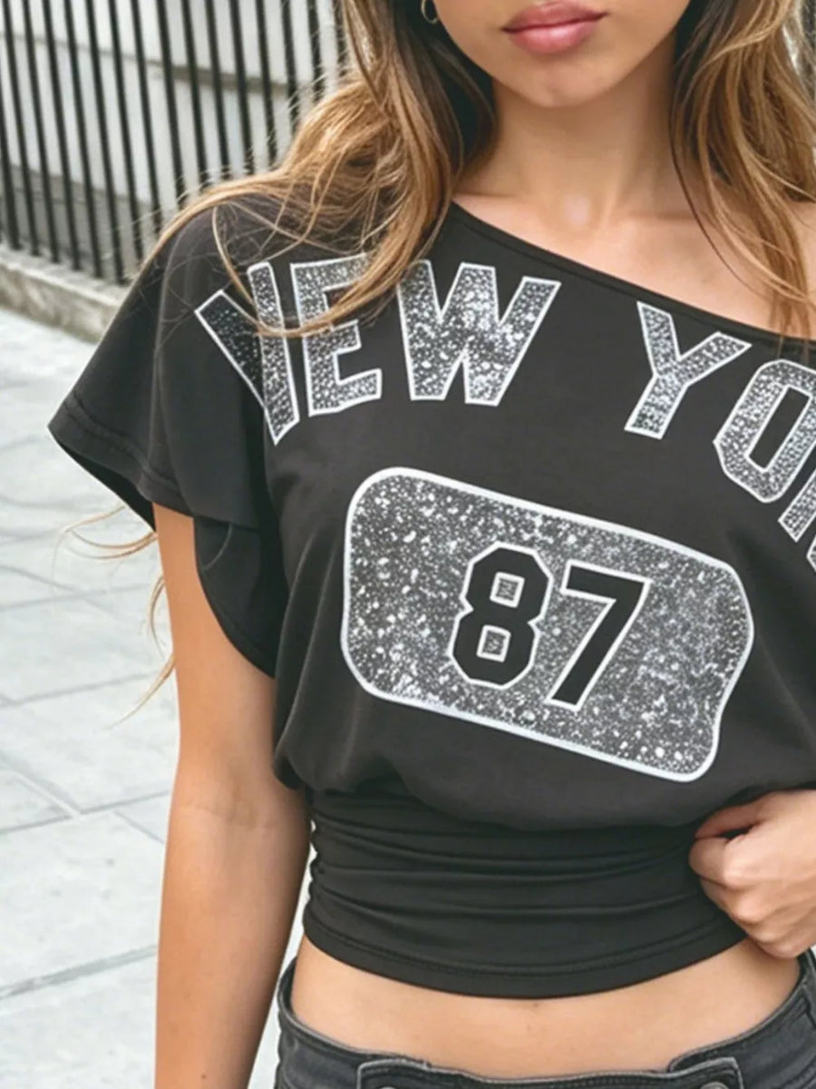 Black one-shoulder top featuring ruched and graphic