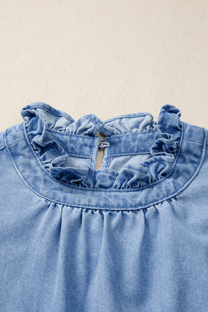 Light wash denim blouse with ruffled collar and button closure at back neck.