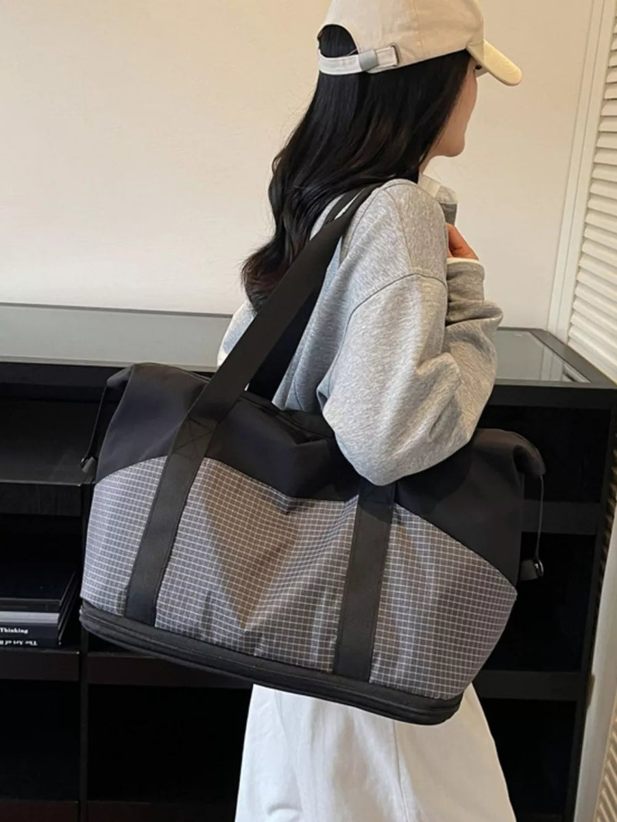 Spacious black and grey checkered nylon travel duffel bag with black straps.