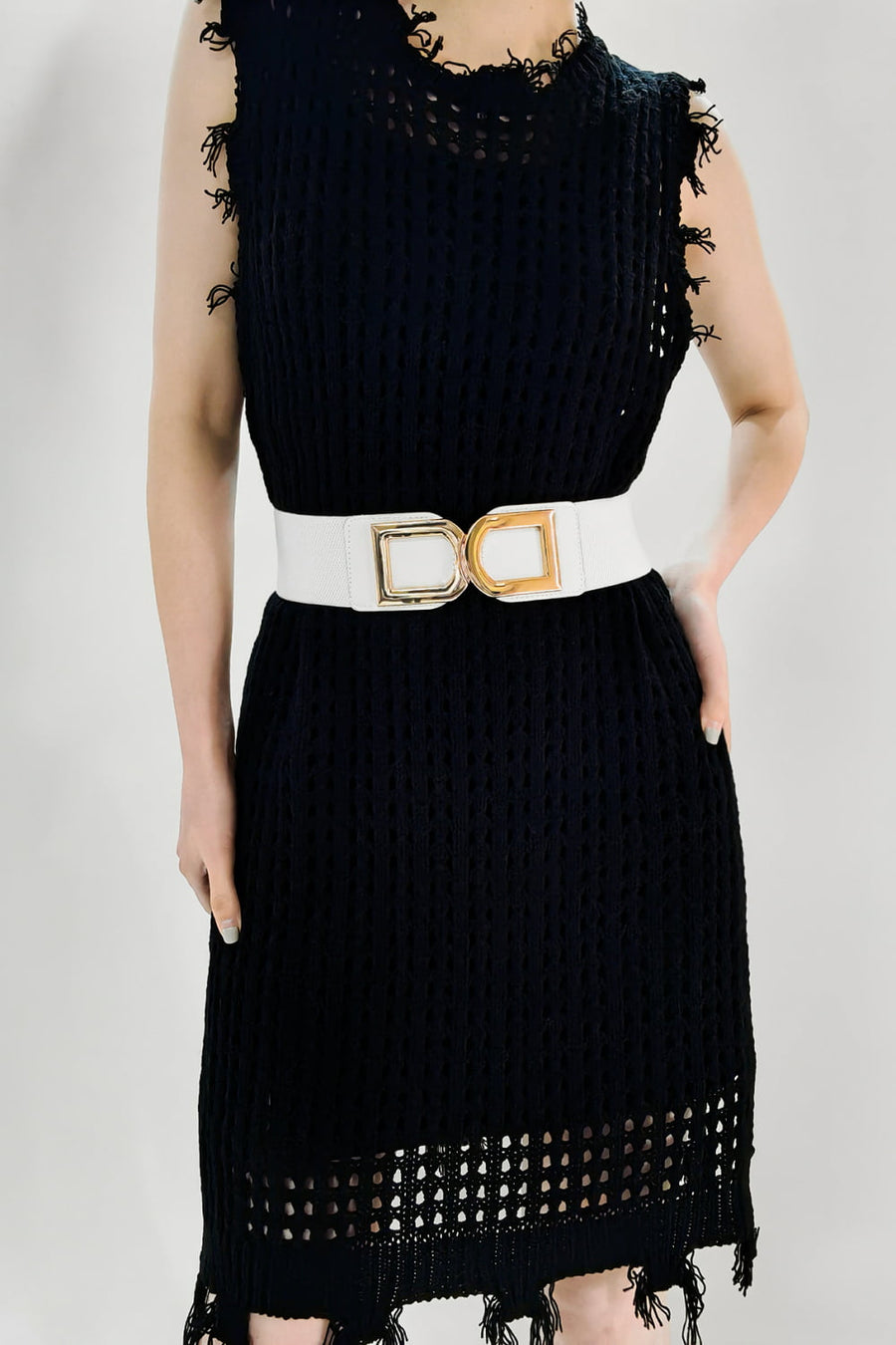 White elastic belt with double gold buckle detail, cinching a black dress.