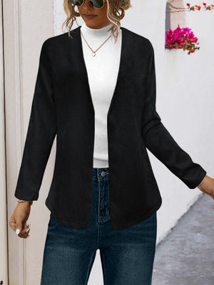 Black suede-effect open front blazer with long sleeves, styled with a white turtleneck and jeans.