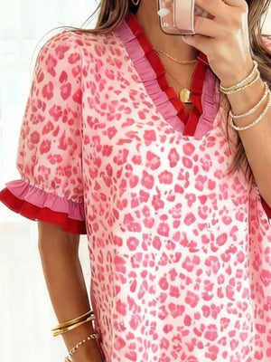 Ruffled pink leopard print blouse with contrast trim and sleeves.