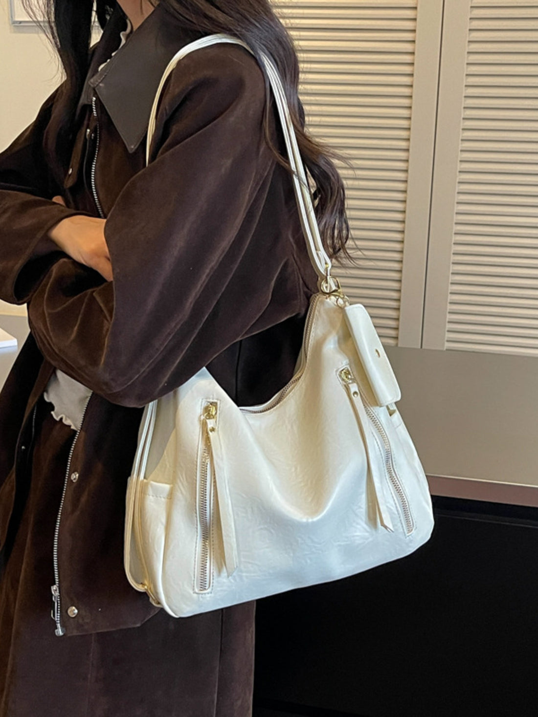 shoulder bag in cream featuring zipper pockets and slouchy fit