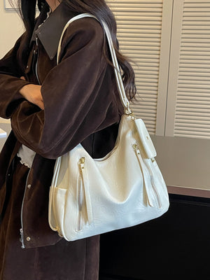 shoulder bag in cream featuring zipper pockets and slouchy fit