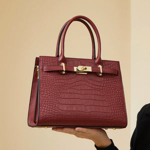 Burgundy crocodile-embossed medium tote handbag with gold hardware and top handles.