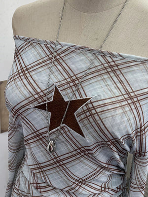 Asymmetrical ruffle hem t-shirt in blue plaid with a brown star detail and off-the-shoulder neckline.