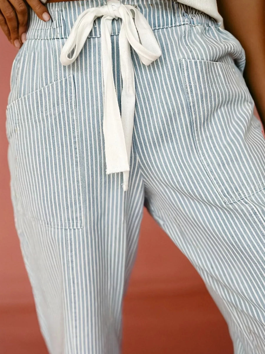 Mid rise drawstring jeans in light blue with white vertical stripes and pockets.
