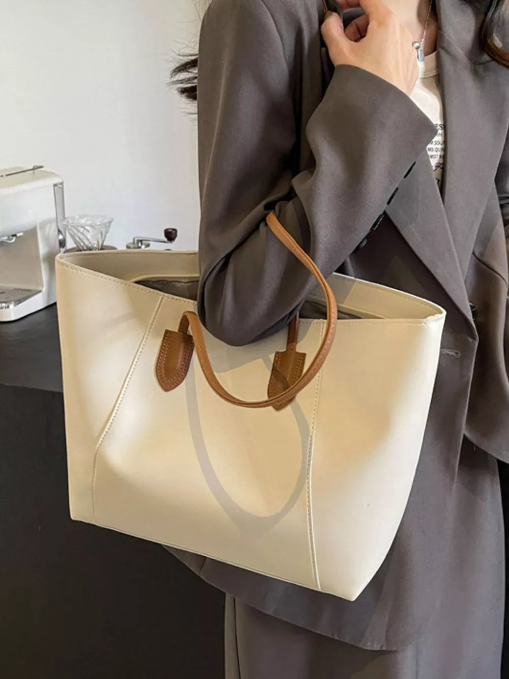 Chic white structured tote bag with tan leather handles and trim, clean silhouette.