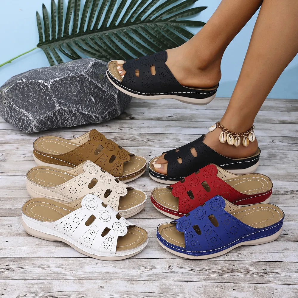 Laser-cut comfort slide sandals in black, red, blue, beige, white, and camel with contoured footbeds.