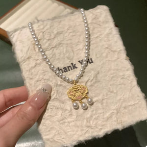 Gold lotus pendant necklace with pearl accents on a pearl strand.
