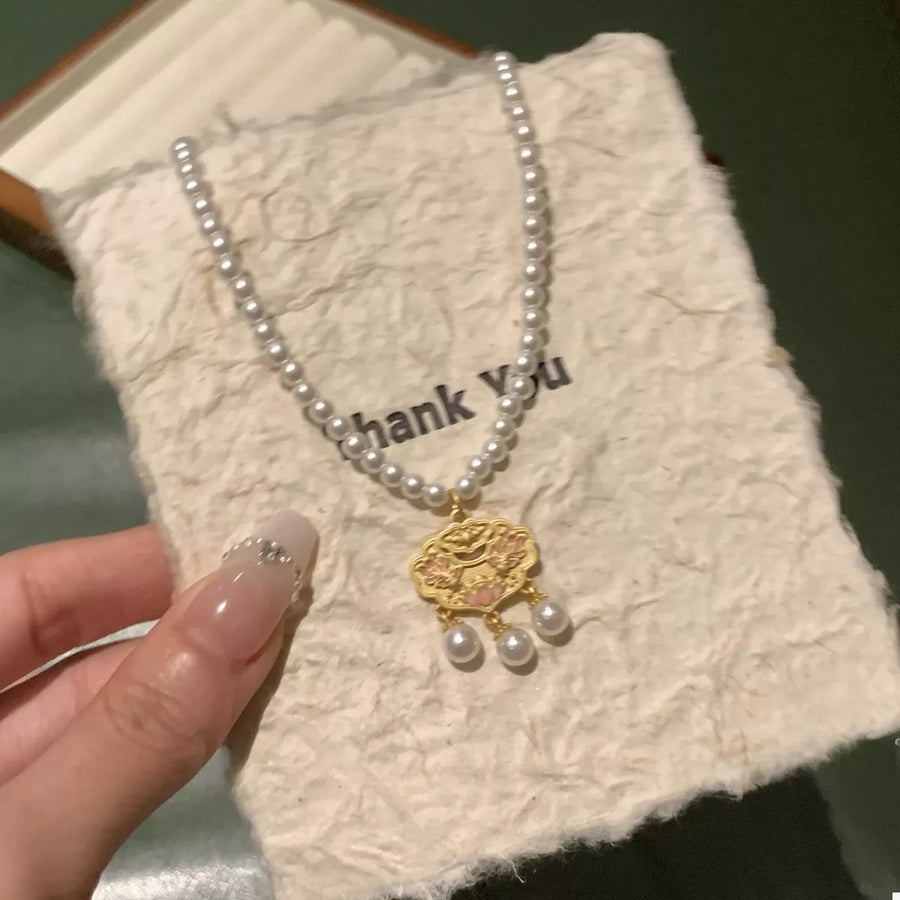 Gold lotus pendant necklace with pearl accents on a pearl strand.