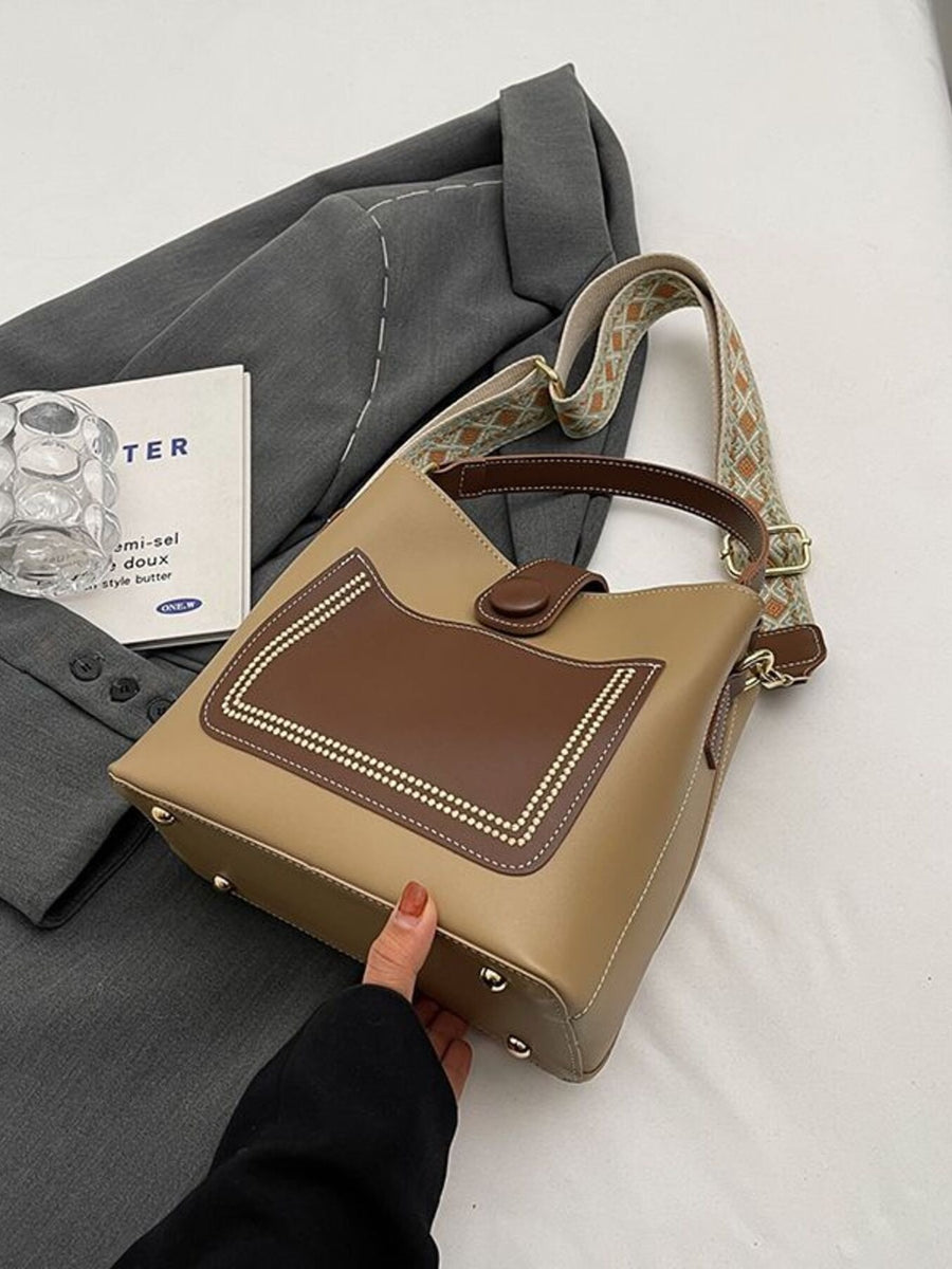 Medium pu leather bucket crossbody bag in brown and tan with decorative stitching and patterned strap.