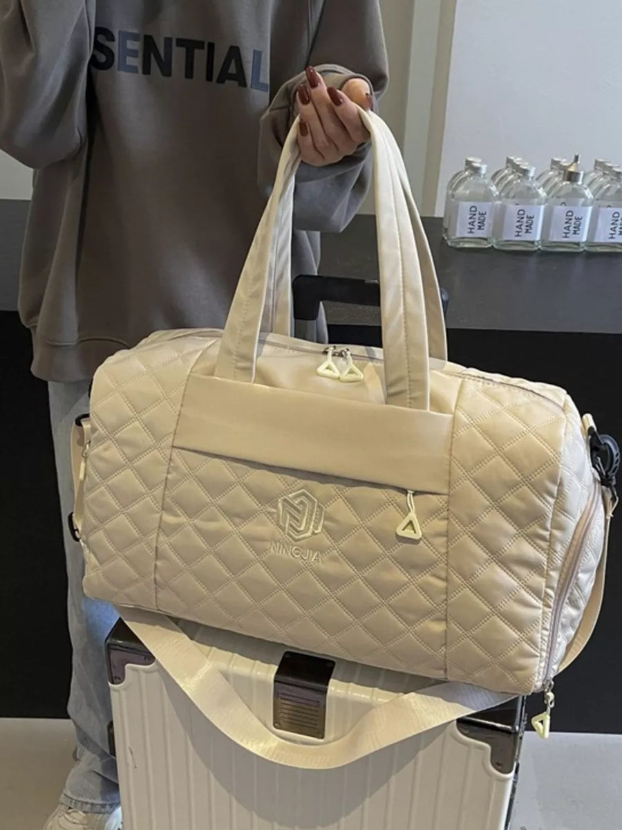 Diamond-stitched beige quilted duffel bag with adjustable strap and front logo detail.