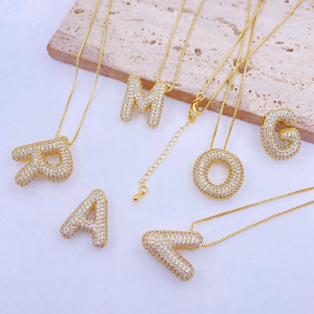 Puffed pave initial pendant necklaces in gold with cubic zirconia, featuring letters R, M, A, O, G, and V.